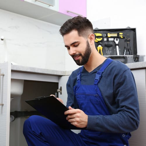 Male plumber with clipboard near kitchen sink. Repair service